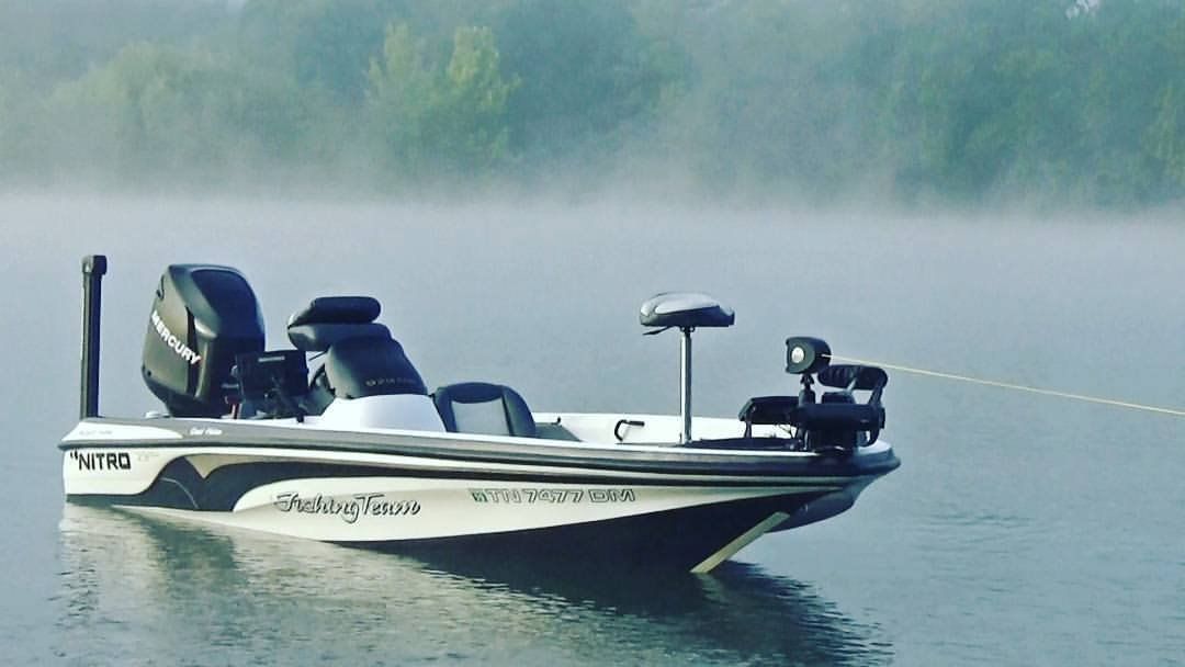 A bass boat on a misty lake, held by a line to shore