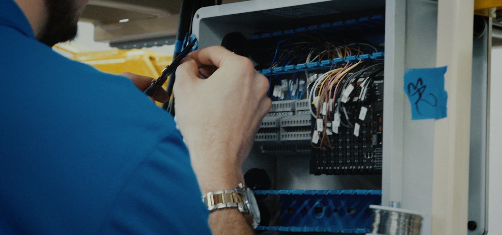 Hands wiring terminal blocks in a control panel
