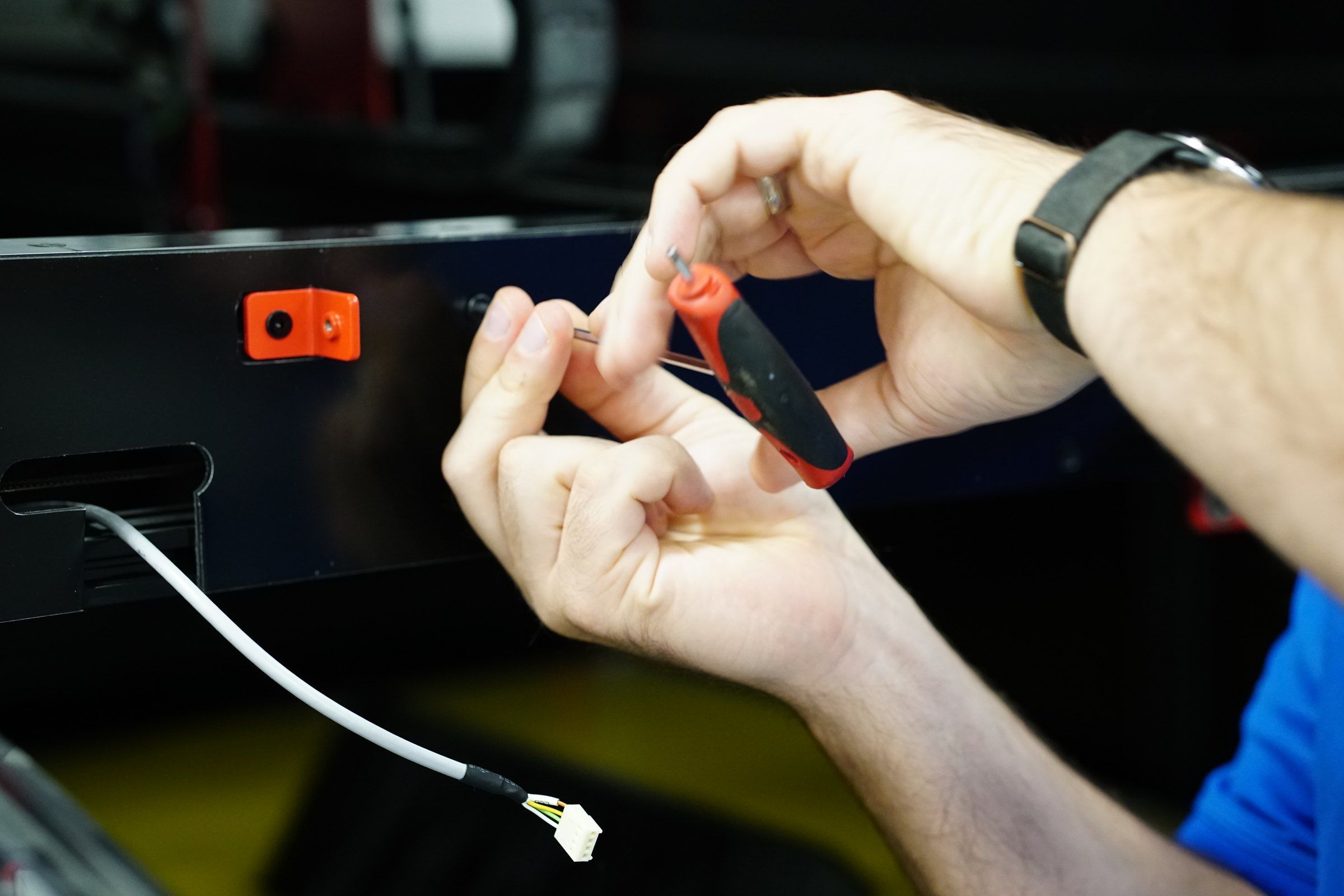 Hands working a small part on a prototype in the APTUS shop