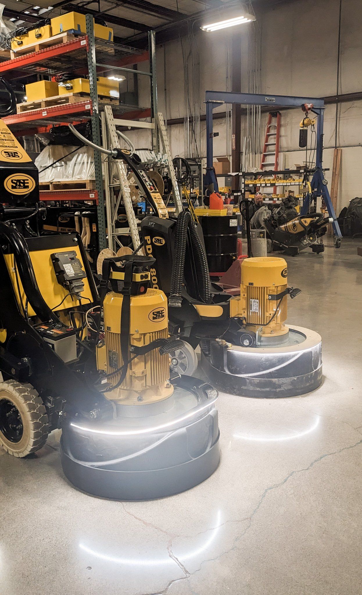 Two yellow SASE grinders side by side on a shop floor, their base lights glowing
